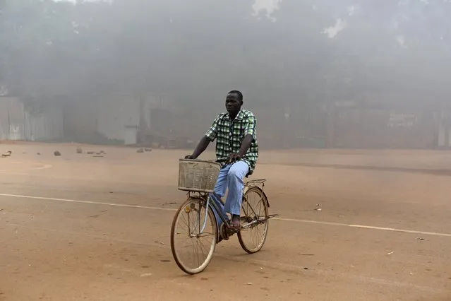 A man on a bicycle rides past a burning roadblock in Ouagadougou, Burkina Faso, September 18, 2015. (Photo by Joe Penney/Reuters)