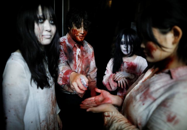 Actors dressed as zombies or ghouls disinfect their hands before their performance at a drive-in haunted house show by Kowagarasetai (Scare Squad), for people inside a car in order to maintain social distancing amid the spread of the coronavirus disease (COVID-19), at a garage in Tokyo, Japan on July 3, 2020. (Photo by Issei Kato/Reuters)