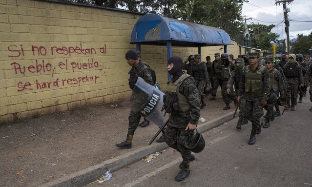 Military police walk past a wall spray painted with a message that reads in Spanish: “if they don't respect the people, the people will force them to show respect”, outside the National Institute of Professional Training, where election ballots are stored, in Tegucigalpa, Honduras, Thursday, November 30, 2017. (Photo by Rodrigo Abd/AP Photo)