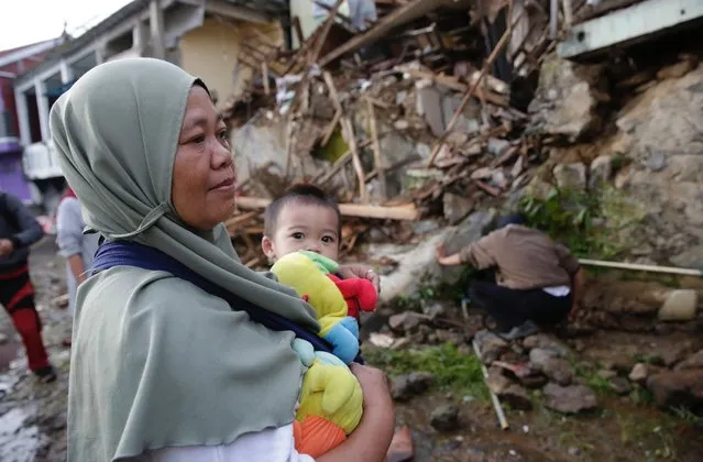 A mother holds her son in front of her damaged house after a 5.6 magnitude earthquake, in Cianjur, Indonesia, 22 November 2022. The earthquake hit the southwest of the Cianjur District in West Java Province, killing 62, according to the Indonesia's National Disaster Management Authority (BNPB). (Photo by Adi Weda/EPA/EFE)