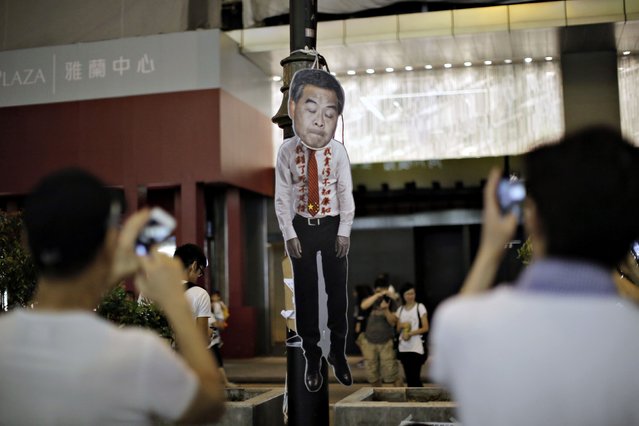 People take pictures of a defaced cutout of Hong Kong Chief Executive Leung Chun-ying at the Mongkok shopping district of Hong Kong October 19, 2014. Violent clashes erupted in Hong Kong early on Sunday for a second night, deepening a sense of impasse between a government with limited options and a pro-democracy movement increasingly willing to confront police. (Photo by Carlos Barria/Reuters)