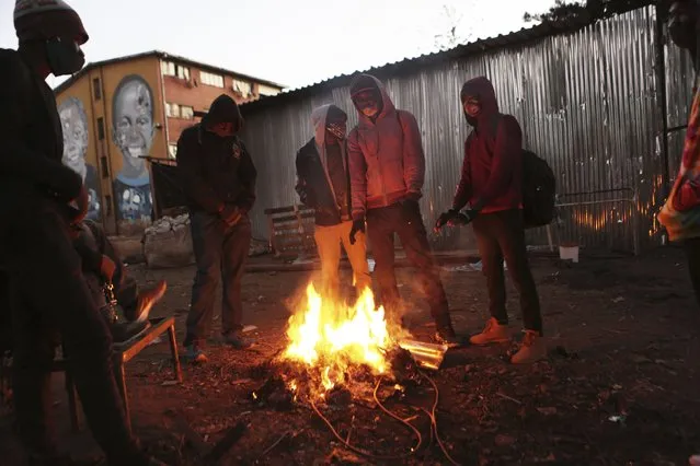 A group of people gather around a fire in a poor neighborhood in Harare, Monday, July 20, 2020. Zimbabwe’s  finance minister says the country's economy is expected to shrink by 4.5% this year, although others say it will contract even more, as the effects of the coronavirus and a drought take a toll on the struggling southern African nation. (Photo by Tsvangirayi Mukwazhi/AP Photo)