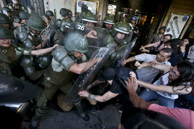 Protesters try to liberate a woman detained by riot police during a protest commemorating the ten year anniversary of the police killing of Mapuche indigenous activist Matias Catrileo, Santiago, Chile, Friday, January 5, 2018. Catrileo was shot to death on Jan. 3, 2008 by a police officer during a land dispute in southern Chile. The officer was sentenced to three years in jail, but served his time on probation. The officer was eventually removed from the police force. (Photo by Esteban Felix/AP Photo)