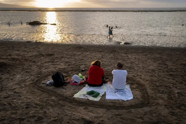 A couple sit at the beach during sunset on the Spanish Gran Canaria island, Spain, Tuesday, August 18, 2020. Spanish authorities have announced new restrictions to help prevent the spreading of COVID-19. (Photo by Emilio Morenatti/AP Photo)