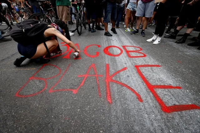 A woman paints the name of Black man Jacob Blake on the street as protesters demonstrate for racial equality in midtown Manhattan following the police shooting in Wisconsin of Blake, in New York City, New York, U.S., August 24, 2020. (Photo by Mike Segar/Reuters)