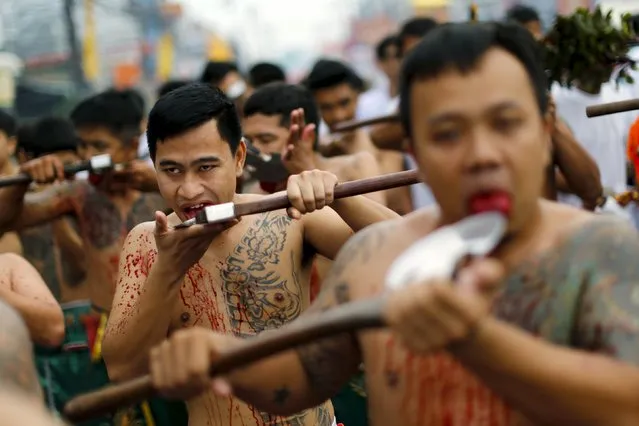 Devotees of the Chinese Samkong Shrine cut their tongues with axes during a procession celebrating the annual vegetarian festival in Phuket, Thailand, October 16, 2015. (Photo by Jorge Silva/Reuters)