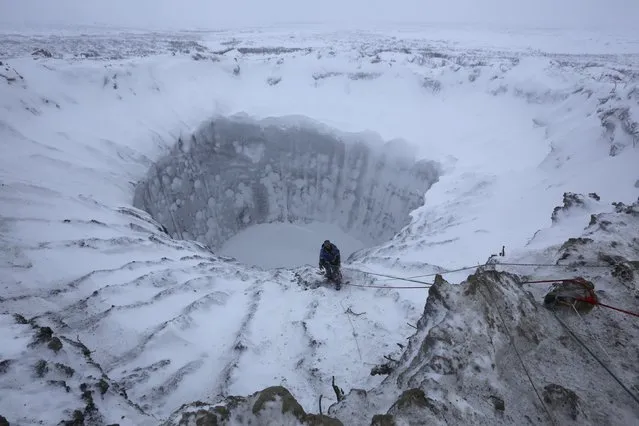 A member of an expedition group stands on the edge of a newly formed crater on the Yamal Peninsula, northern Siberia November 9, 2014. (Photo by Vladimir Pushkarev/Reuters/Russian Centre of Arctic Exploration)