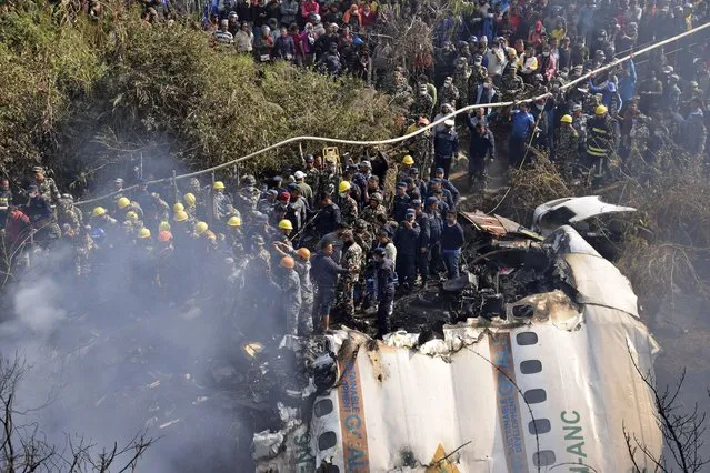 Nepalese rescue workers and civilians gather around the wreckage of a passenger plane that crashed in Pokhara, Nepal, Sunday, January 15, 2023. Authorities in Nepal said 68 people have been confirmed dead after a regional passenger plane with 72 aboard crashed into a gorge while landing at a newly opened airport in the resort town of Pokhara. It's the country's deadliest airplane accident in three decades. (Photo by Krishna Mani Baral/AP Photo)