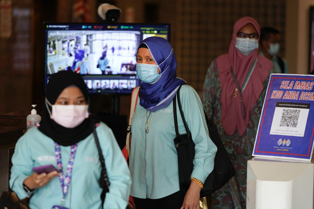 Employees wearing face masks to help curb the spread of the coronavirus leave their office in Kuala Lumpur, Malaysia, Monday, October 26, 2020. Senior Minister Ismail Sabri Yaakob announce conditional movement control order (MCO) in Kuala Lumpur, Selangor and Putrajaya will be extended for another two weeks until Nov. 9. (Photo by Vincent Thian/AP Photo)
