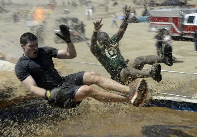 People hit muddy waters at full speed during the “Tough Mudder” obstacle course event in San Bernardino, California March 29, 2014. The event is part of a worldwide tour of extreme obstacle challenges before finishing with the annual “World's Toughest Mudder” competition. (Photo by Gene Blevins/Reuters)