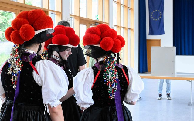 Woman wearing traditional “Bollenhut” pompon hats, typical for the Black Forest region, line up to fill out their ballot papers for European Parliament Elections at a polling station in Gutach, southern Germany, on June 9, 2024. (Photo by Thomas Kienzle/AFP Photo)