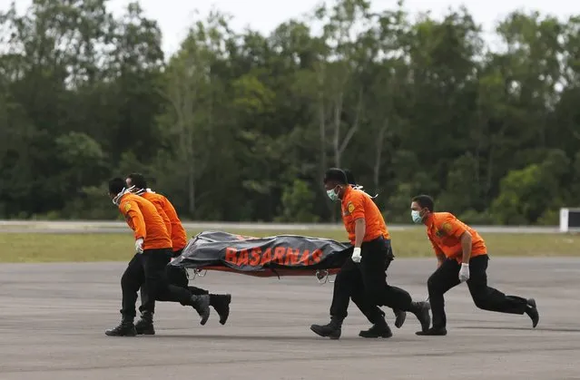 Search and rescue team members run as carry the dead body of a passenger onboard AirAsia flight QZ8501 at Iskandar airbase in Pangkalan Bun, Indonesia, December 31, 2014. A sonar image showing a large, dark object on the sea bed is believed to be a missing AirAsia plane, an official with Indonesia's search and rescue agency said on Wednesday after bodies and debris were found in the area. (Photo by Reuters/Beawiharta)