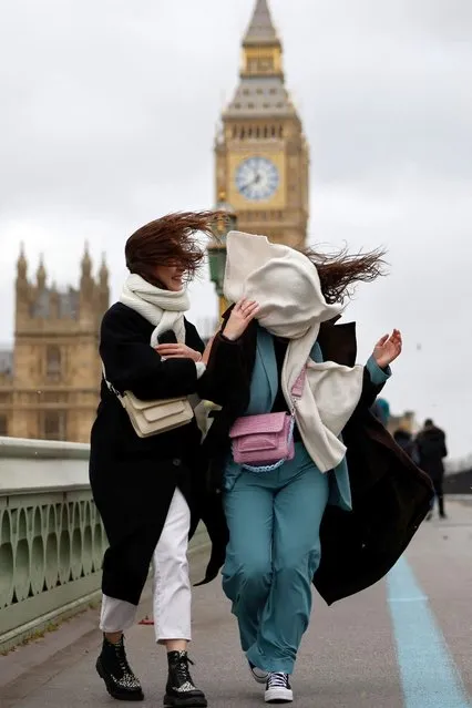 People struggle in the wind as they walk across Westminster Bridge, near the Houses of Parliament in central London, on February 18, 2022, as Storm Eunice brings high winds across the country. Britain put the army on standby Friday and schools closed as forecasters issued two rare “red weather” warnings of “danger to life” from fearsome winds and flooding due to the approaching storm Eunice. (Photo by Tolga Akmen/AFP Photo)