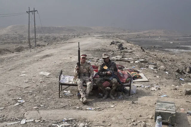 Iraqi army soldiers rest at a checkpoint in Qayara, some 50 kilometers south of Mosul, Iraq, Wednesday, October 26, 2016. Islamic State militants have been going door to door in farming communities south of Mosul, ordering people at gunpoint to follow them north into the city and apparently using them as human shields as they retreat from Iraqi forces. Witnesses to the forced evacuation describe scenes of chaos as hundreds of people were driven north across the Ninevah plains and into the heavily-fortified city, where the extremists are believed to be preparing for a climactic showdown. (Photo by Marko Drobnjakovic/AP Photo)