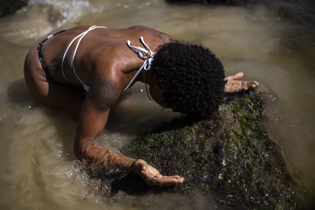 Shirley Azedi, who said she's lost work as a housekeeper due to the COVID-19 pandemic, prays during a ceremony in honor of the Goddess of the Sea Yemanja on Praia Vermelha beach to mark the end of the year in Rio de Janeiro, Brazil, on New Year's Eve, Thursday, December 31, 2020. Beaches will be closed on the night of new year's, to help curb the spread of the new coronavirus. (Photo by Bruna Prado/AP Photo)