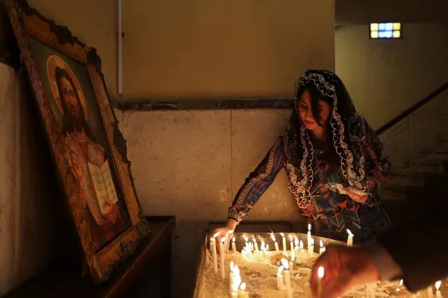 A Christian woman lights a candle during an Easter mass at the Armenian church in Baghdad, Iraq on April 9, 2023. (Photo by Tiba Sadeq/Reuters)