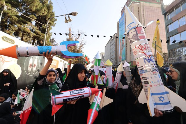 Women hold model missiles during a rally outside the former US embassy in Tehran as Iranians mark the 46th anniversary of the start of the Iran hostage crisis, on November 4, 2025. In 1979, 52 embassy staff were held hostage for 444 days by Iranian students, who demanded that Washington hand over Iran's recently toppled shah, who was being treated in the United States for cancer. (Photo by Atta Kenare/AFP Photo)