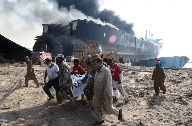 Pakistani security officials carry a body of victim who was killed in an explosion at ship breaking yard in Gaddani, Pakistan, 01 November 2016. Reports state that at least nine workers were killed and more than 100 were wounded in a blast at Gaddani ship breaking yard near Karachi on 01 November. (Photo by Rehan Khan/EPA)