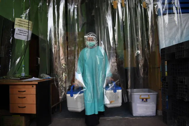 A health worker delivers containers of Covid-19 vaccines produced by China's Sinovac, from a cold room in Bandung on January 13, 2021, as the sprawling archipelago of nearly 270 million kicks off a mass innoculation drive in a bid to control soaring case rates. (Photo by Timur Matahari/AFP Photo)