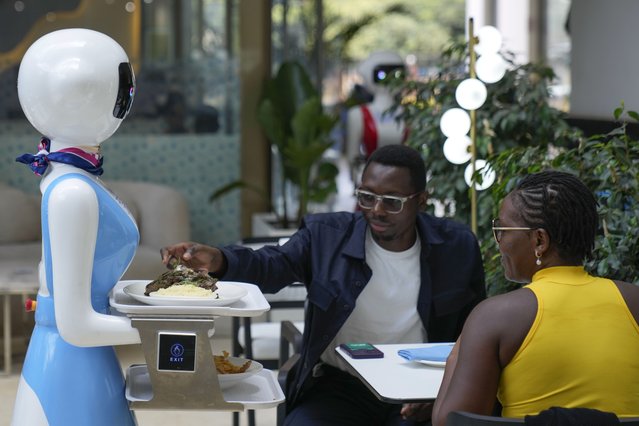 Robotic waiter Claire, delivers an order to customers at the Robot Cafe in Nairobi, Kenya Thursday, August 29, 2024. The three robots, christened Claire, R24 and Nadia, are not programmed to have a full conversation with customers, but they can say “Your order is ready, Welcome” then people have to press an exit button after picking up their food from the tray. (Photo by Brian Inganga/AP Photo)