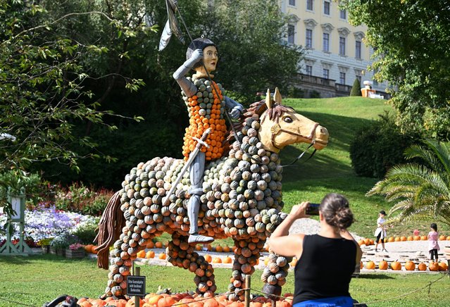 A woman makes a picture of an exhibit depicting French national heroine Jeanne d'Arc on display at a pumpkin exhibition themed “Strong women” in the garden of Ludwigsburg Castle in Ludwigsburg, southern Germany, on August 22, 2024. (Photo by Thomas Kienzle/AFP Photo)