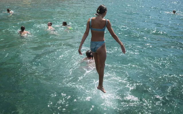 A girl jumps off the breakwater into the Black Sea in the Crimean village of Beregove, Ukraine, on June 20, 2013. (Photo by Gleb Garanich/Reuters)