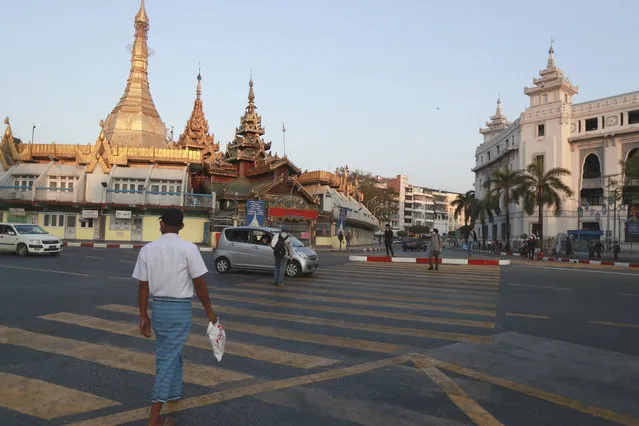 People cross a road near Sule Pagoda Monday, February 1, 2021 in Yangon, Myanmar. A military coup was taking place in Myanmar early Monday and State Counsellor Aung San Suu Kyi was detained under house arrest, reports said, as communications were cut to the capital. (Photo by Thein Zaw/AP Photo)