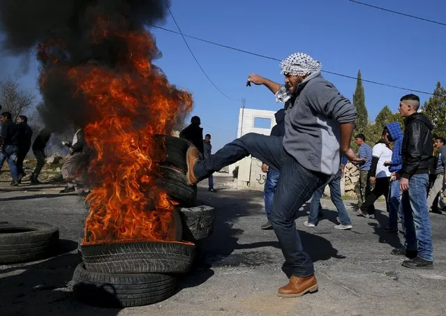 A Palestinian protester pushes burning tyres during clashes with Israeli troops in the West Bank village of Silwad, near Ramallah, December 11, 2015. (Photo by Ammar Awad/Reuters)