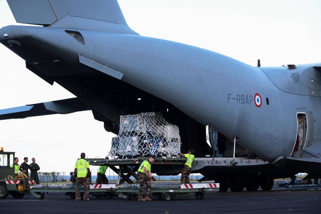 French military unload medical and emergency equipment from the A440M military aircraft, aboard of wich rescue teams were transported in an emergency response, bringing aid to the small French Indian Ocean territory of Mayotte, almost cut off from the world after the passage of cyclone Chido, at the French Air Force Base 181 Saint-Denis-La Reunion “Lieutenant Roland Garros” in Sainte-Marie, on the French Indian Ocean island of La Reunion, on December 15, 2024. At least 14 people were killed in Mayotte when a fierce cyclone battered the territory, authorities said, with officials warning it will take days to know the full toll. Rescue workers and supplies are being rushed in by air and sea, but their efforts are likely to be hindered by damage to airports and electricity distribution in a territory where even clean drinking water was already subject to chronic shortages. (Photo by Richard Bouhet/AFP Photo)