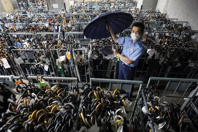 A police officer holds an umbrella at the Lost and Found Center of the Metropolitan Police Department in Tokyo, Japan, 19 June 2023. During the rainy season, it is estimated that some 2,000 umbrellas per rainfall are forgotten in trains, especially on subways. (Photo by JIJI Press/EPA)