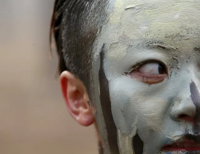 A model painted in camouflage colours to blend in with the background waits to pose for Chinese artist Liu Bolin's artwork “Dongji”, or Winter Solstice, on the second day after China's capital Beijing issued its second ever “red alert” for air pollution, in Beijing, China, December 20, 2015. (Photo by Kim Kyung-Hoon/Reuters)