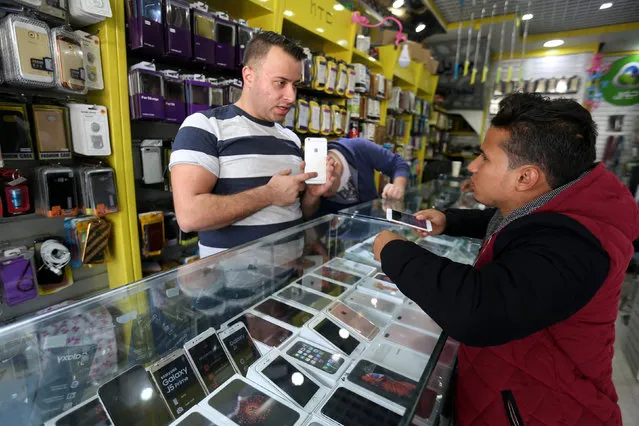 A Palestinian seller shows a smartphone to a customer in a mobile phone shop in Gaza City November 16, 2016. (Photo by Ibraheem Abu Mustafa/Reuters)