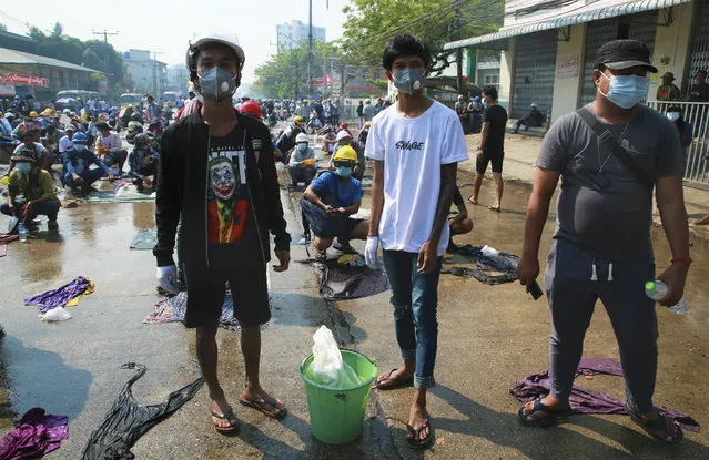 Anti-coup protesters prepare water and wet cloths to help extinguish tear gas canisters during a demonstration in Yangon, Myanmar, Saturday, March 6, 2021. Security forces in Myanmar  used force again Saturday to disperse anti-coup protesters, a day after the U.N. special envoy urged the Security Council to take action to quell junta violence that this week left about 50 peaceful demonstrators dead and scores injured. (Photo by Reuters/Stringer)