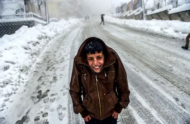 A Kurdish boy protects himself against the cold as heavy snow fall hits the city of Sirnak, southeastern Turkey, on January 1, 2016. Tensions are running high throughout Turkey's restive southeast as security forces impose curfews in several towns including Cizre in a bid to root out Kurdistan Workers' Party (PKK) rebels from urban centres. (Photo by Bulent Kilic/AFP Photo)