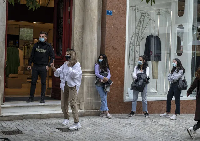Customers wearing protective face masks queue outside a clothing store in Ermou street, central Athens, on Monday, April 5, 2021. Retail stores across most of Greece have been allowed to reopen despite an ongoing surge in COVID-19 infections, as the country battled to emerge from deep recession. (Photo by Petros Giannakouris/AP Photo)