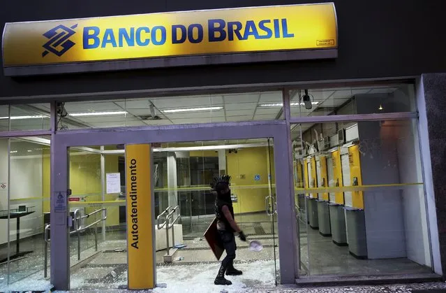 A demonstrator attacks a Brasil bank branch during a protest against fare hikes for city buses in Sao Paulo, Brazil, January 8, 2016. (Photo by Nacho Doce/Reuters)