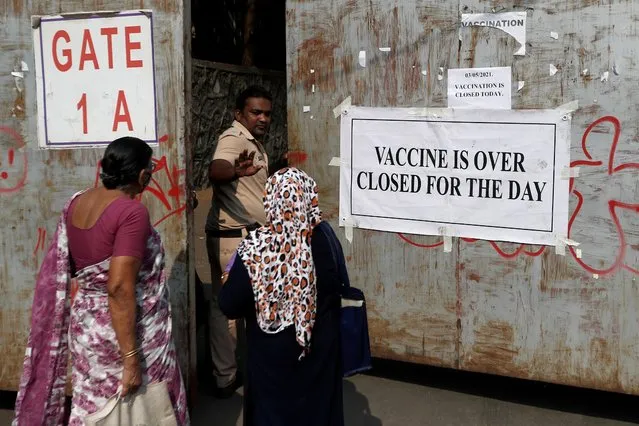 A policeman asks people who came to receive a dose of a coronavirus vaccine to leave as they stand outside the gate of a vaccination centre which was closed due to a lack of supply of the COVID-19 vaccine, in Mumbai, India, May 3, 2021. (Photo by Francis Mascarenhas/Reuters)