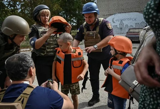 Police officers put body armour on children before evacuation from their village near the front line, amid Russia's attack on Ukraine, in the village of Stepnohirsk in Zaporizhzhia region, Ukraine on August 31, 2023. (Photo by Reuters/Stringer)