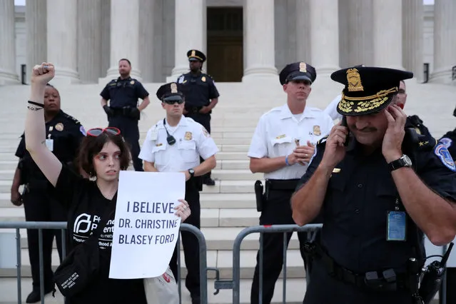 A protester holds a sign reading “I Believe Dr Christine Blasey Ford” as she stands with police after they cleared the steps of the U.S. Supreme Court building of demonstrators while Judge Brett Kavanaugh was being sworn in as an Associate Justice of the court inside on Capitol Hill in Washington, U.S., October 6, 2018. (Photo by Jonathan Ernst/Reuters)