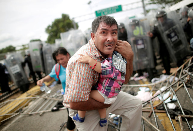 A Honduran migrant protects his child after fellow migrants, part of a caravan trying to reach the U.S., stormed a border checkpoint in Guatemala, in Ciudad Hidalgo, Mexico October 19, 2018. (Photo by Ueslei Marcelino/Reuters)