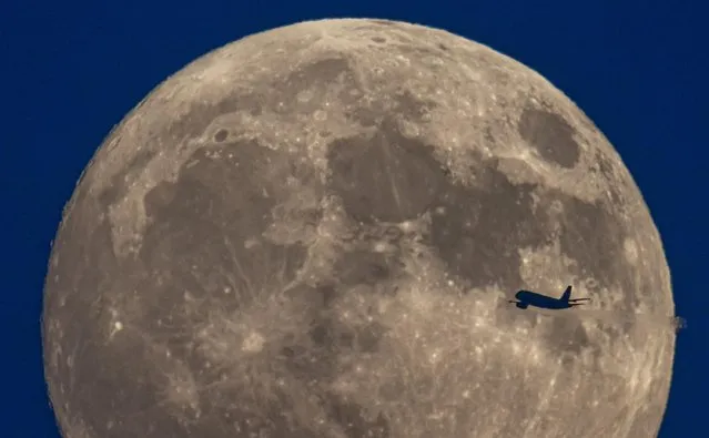 A passenger plane over London on Tuesday, June 14, 2022 is silhouetted against a sensational “strawberry” supermoon, so named because it coincides with berries ripening for harvest. (Photo by Peter Macdiarmid/London News Pictures)