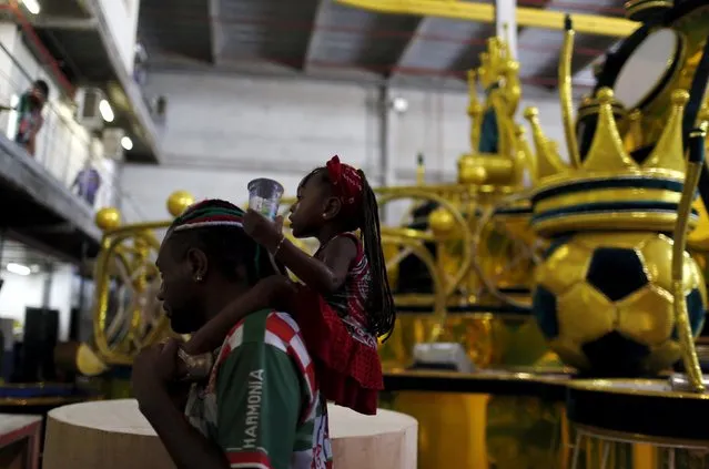 A man carrying a child walks past in front of a carnival float at the Grande Rio Samba school in Rio de Janeiro, Brazil, January 26, 2016. (Photo by Pilar Olivares/Reuters)