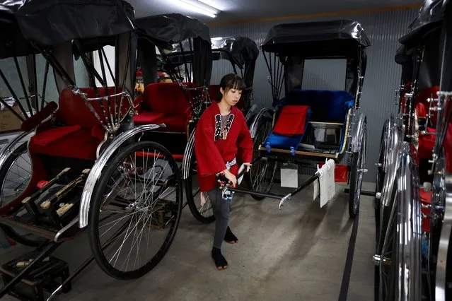 Rickshaw puller Yuka Akimoto, 21, prepares her rickshaw in a garage at the Asakusa district, Tokyo, Japan on August 22, 2023. Akimoto is one of a handful of women who have chosen to pull rickshaws in Tokyo, attracted to the male-dominated profession through social media, which in turn has given some of these female pullers a strong local and international following. “I don't deny it was extremely hard at the beginning”, she said, as the rickshaw can weigh up to 250 kg (551 lb). “I'm not athletic and the cart felt so heavy”. (Photo by Issei Kato/Reuters)