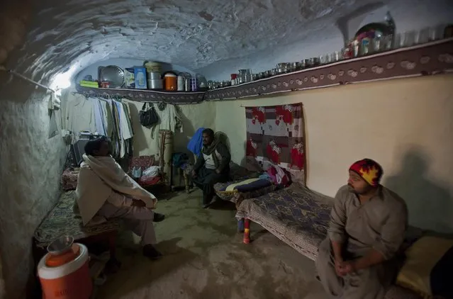 In this Friday, December 16, 2016 photo, a Pakistani Mohammad Ramzan, left, talks with friends in his cave home locally called “Bhora”, in Hasan Abdal, some 60 kilometers (35 miles) north of the capital Islamabad, Pakistan. Ramzan's family lives in one the dozens cave homes, which are equipped with all modern amenities and cool even on the hottest summer day and warm in winter nights, built by their forefathers in surroundings of the town of Hasan Abdal. Dug out of hard clay and earth, these cave homes are man-made, not natural formations which served as one of the earliest dwellings. (Photo by Anjum Naveed/AP Photo)