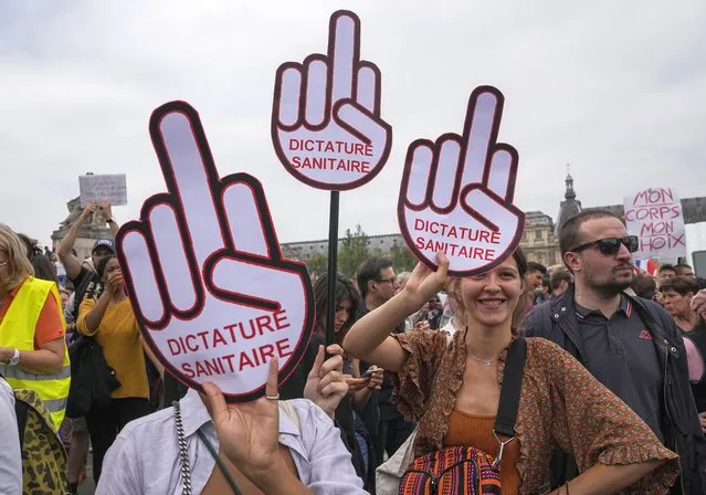Anti-vaccine protesters hold placard that reads health dictatorship during a rally in Paris, Saturday, July 17, 2021. Tens of thousands of people protested across France on Saturday against the government's latest measures to curb rising COVID-19 infections and drive up vaccinations in the country. (Photo by Michel Euler/AP Photo)