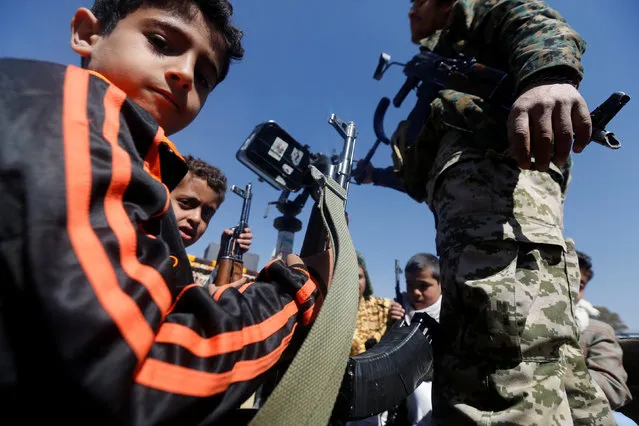 Boys hold rifles as they ride on the back of a military truck during a parade held by newly recruited Houthi fighters in Sanaa, Yemen, January 1, 2017. (Photo by Khaled Abdullah/Reuters)