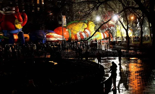 Sightseers throng past giant balloons being prepared for the parade. (Photo by John Moore/Getty Images)