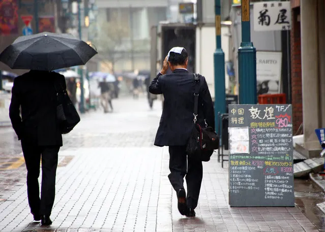 A man covers his head with a handkerchief as he makes his way in the rain at a shopping district in Tokyo, Japan October 28, 2016. (Photo by Kim Kyung-Hoon/Reuters)