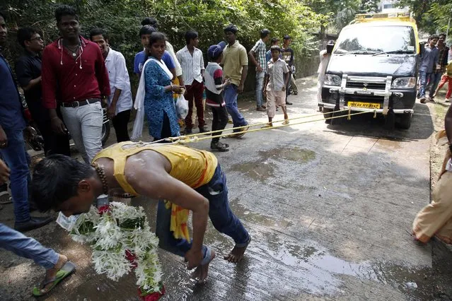 A Indian Hindu devotee pulls a car with metal hooks pierced into his back during a religious procession to the temple of Hindu goddess Muthumariamman in Mumbai, India, Saturday, March 28, 2015. The devotees perform the ritual after their prayers to the goddess have been answered or their wishes fulfilled. (Photo by Rajanish Kakade/AP Photo)