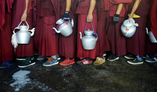 Tibetan Buddhist monks wait to collect boiling milk to distribute to devotees who are participating in a special religious prayer attended by Tibetan spiritual leader The Dalai Lama during the Kalachakra event at Bodhgaya on January 4, 2017. (Photo by Dibyangshu Sarkar/AFP Photo)